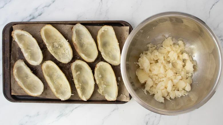A baking sheet containing potato skins and a large bowl containing the potato flesh