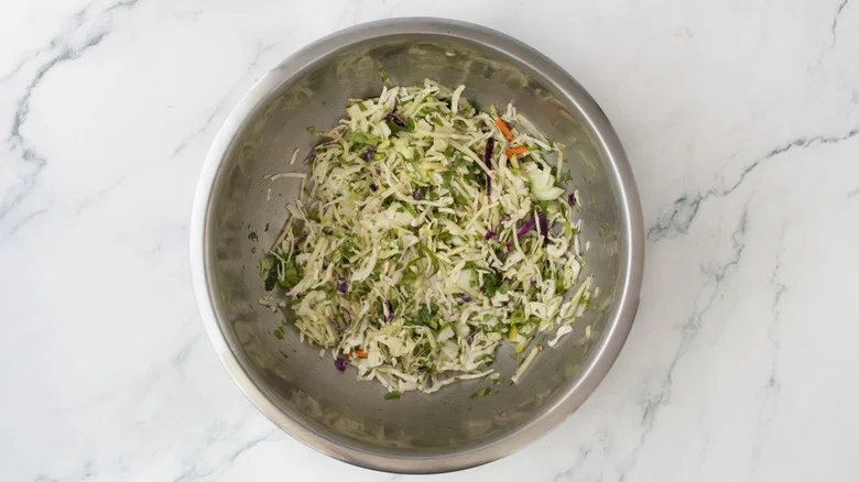 A composed coleslaw in a large metal bowl