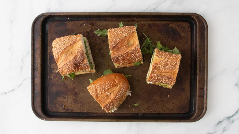 Four portions of tuna salad sandwiches on a baking sheet.