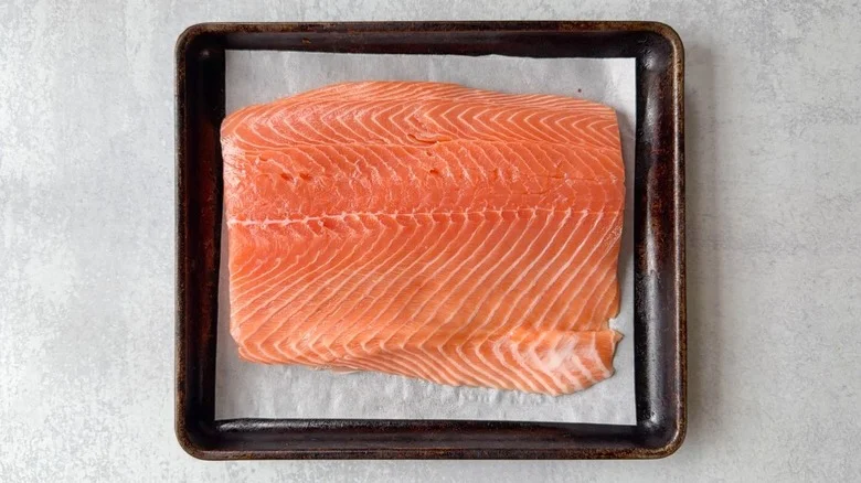 Fresh salmon filet on parchment-lined baking sheet
