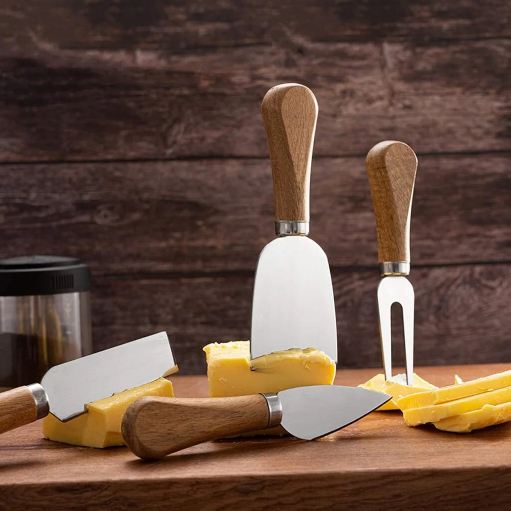 4 cheese knives on a wood cutting board