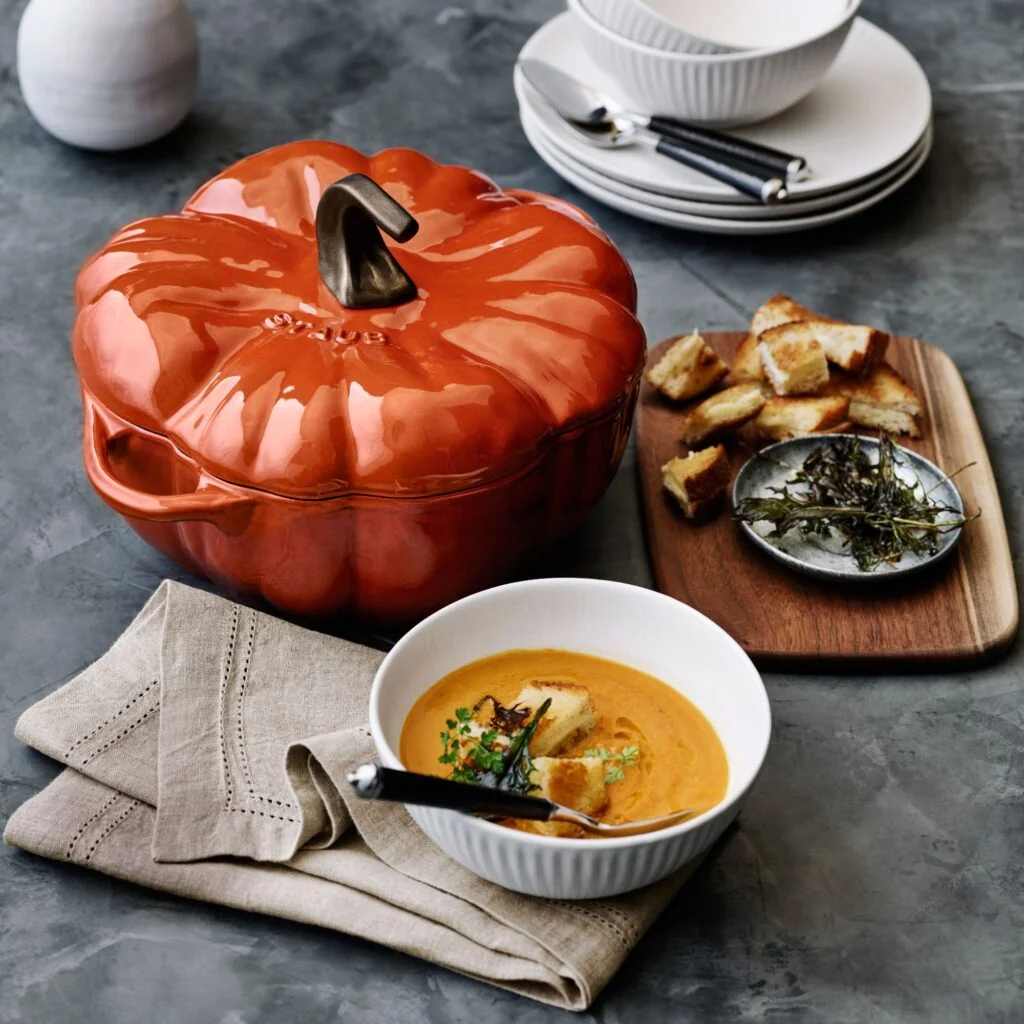 Pumpkin dish next to a bowl of soup and bread serving tray